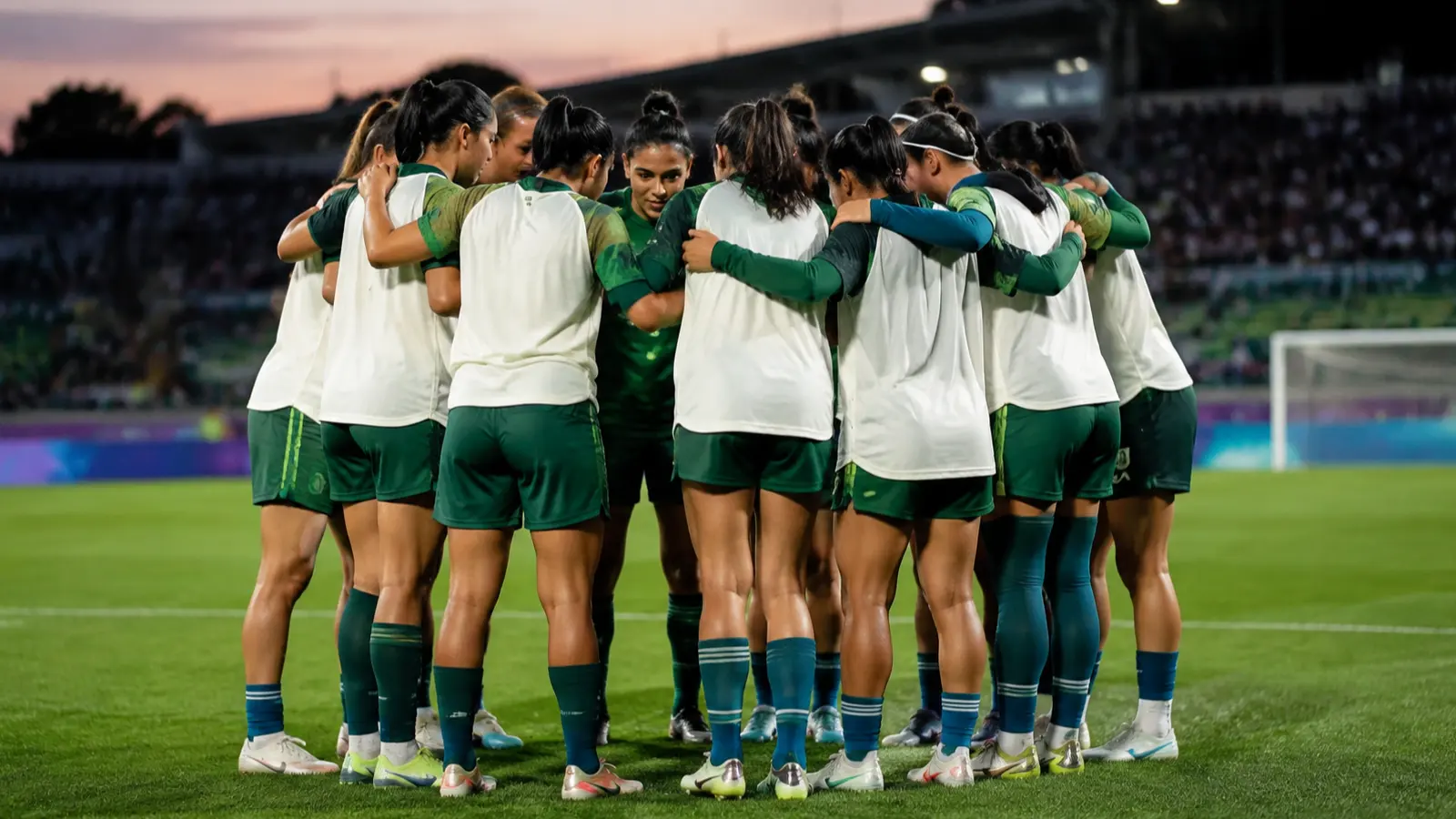 Futbolistas juveniles con uniforme verde y blanco reunidas en una cancha