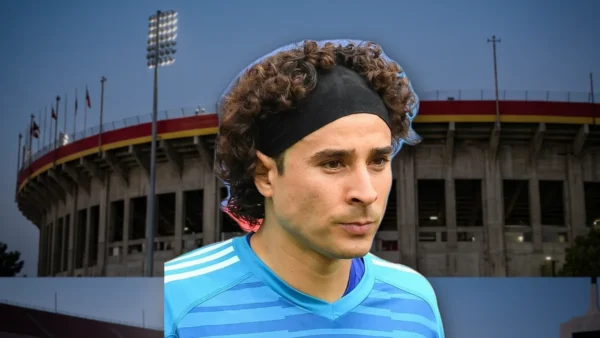 Pebetero olímpico encendido en un estadio, con un cielo azul de fondo.